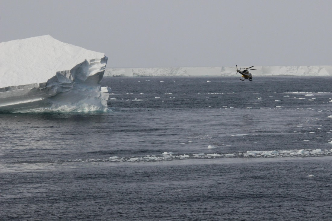 Helicopter passing iceberg near the Ross Ice Shelf