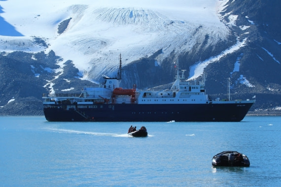 Zodiacs cruising to the landing site with the MV Ortelius in the back laying in front of the Tindebreen